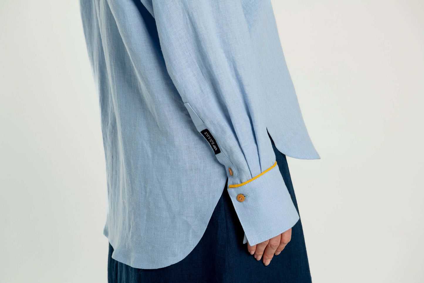 Oversized linen shirt with yellow details Brillante showcasing blue linen fabric and unique cuff design.