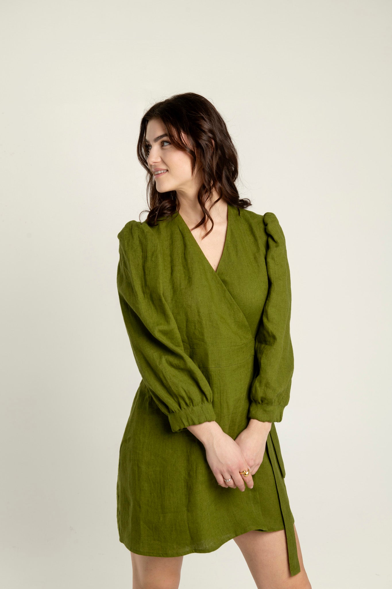 Olive green Madeleine crossover linen mini dress with pockets with puffed long sleeves and V-neckline.