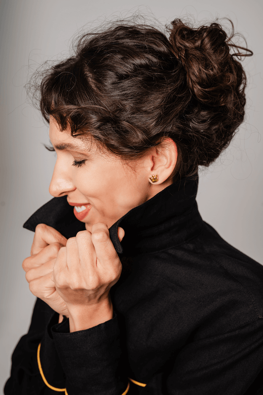 Woman in a stylish black coat modeling porcelain earrings and linen clothing for a chic look.