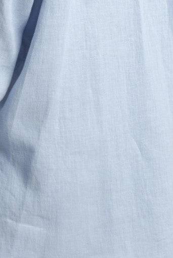 Close-up of soft baby blue 100% natural softened linen fabric texture on the Madeleine crossover linen mini dress with pockets.