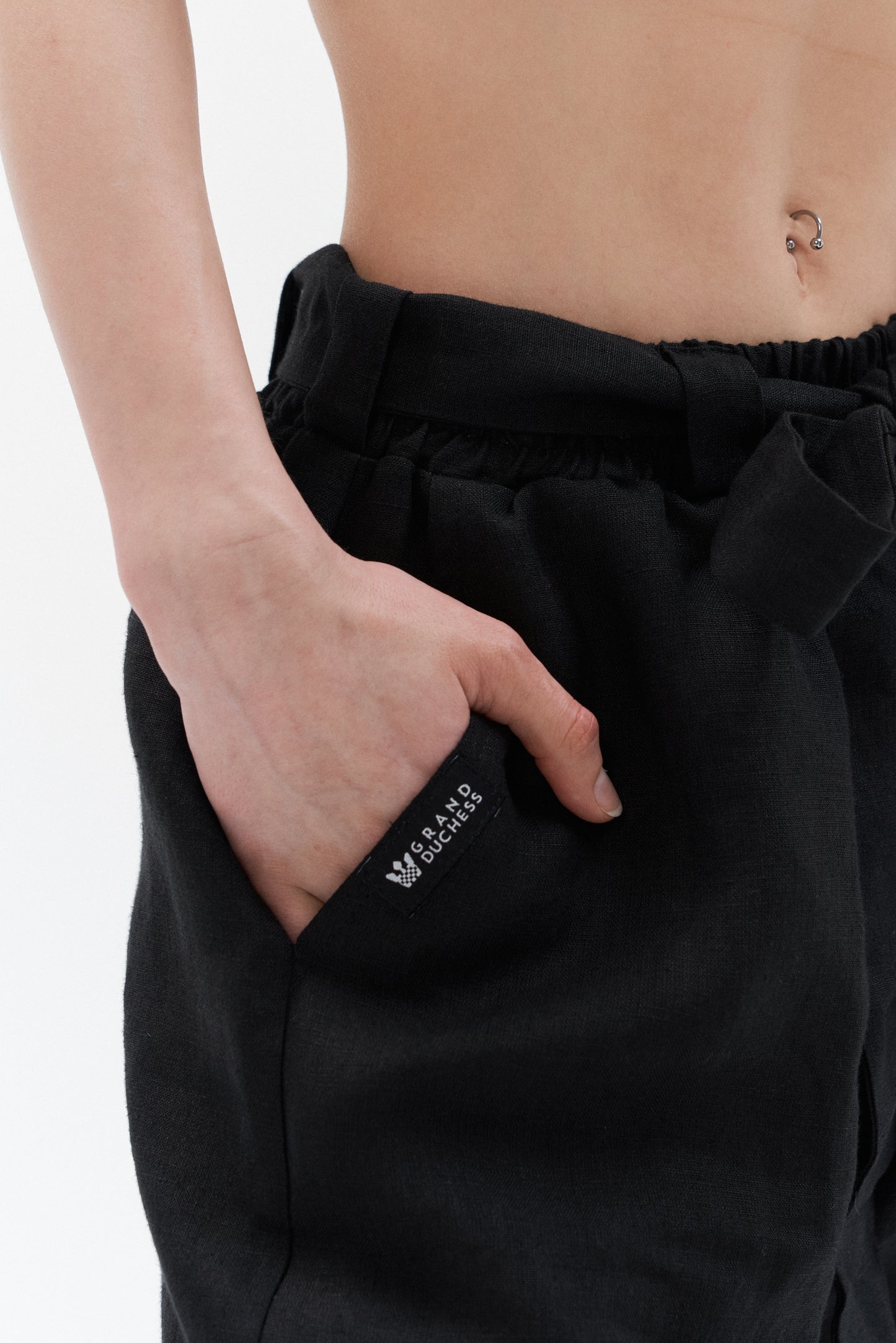Grand Duchess black women's linen pants – detail of pocket with logo label, wide-leg sustainable trousers with belt.