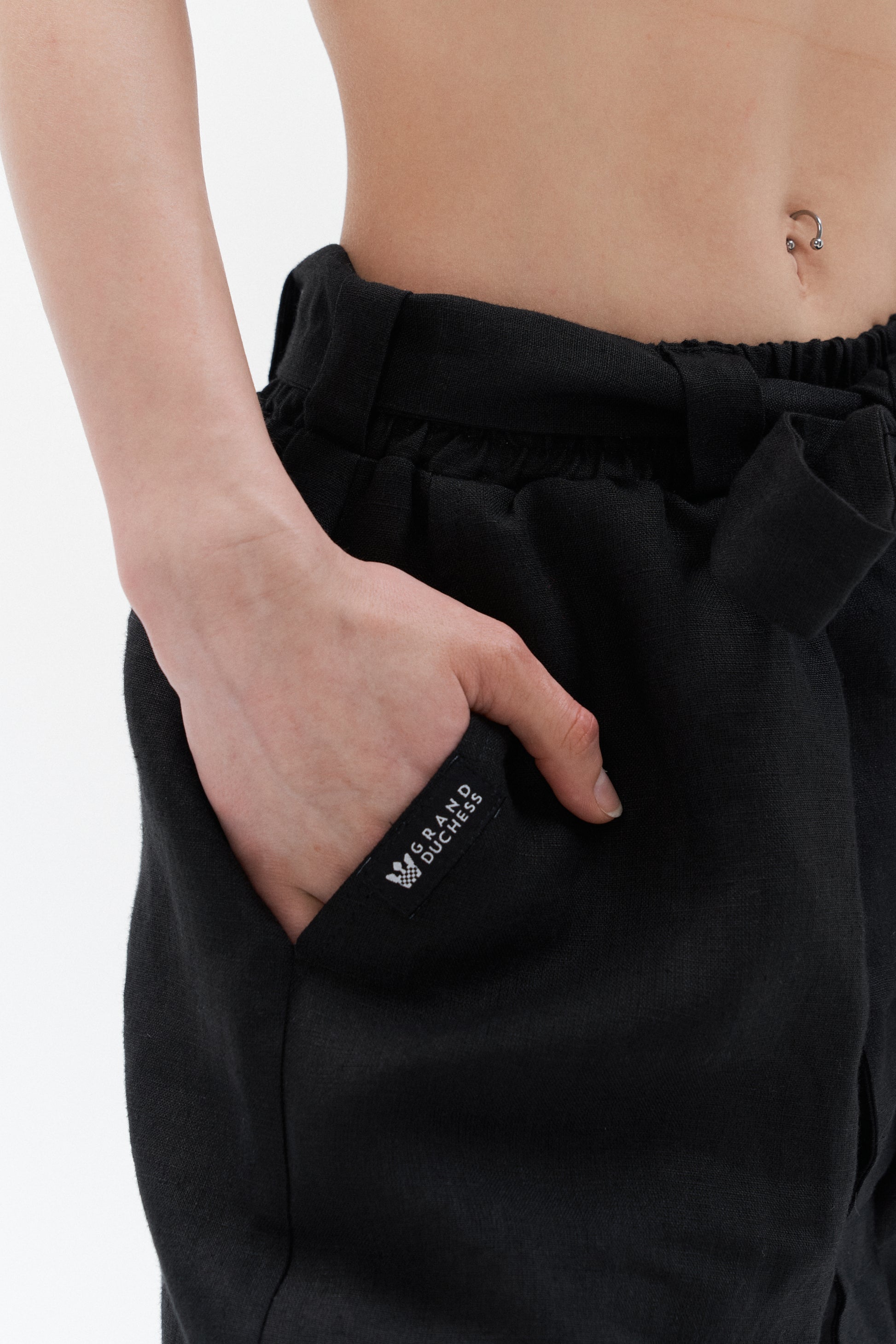 Grand Duchess black women's linen pants – detail of pocket with logo label, wide-leg sustainable trousers with belt.